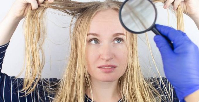 Mujer observa con lupa su pelo grasoso