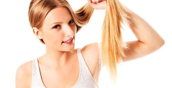 mujer sostiene un mechón de pelo naranja en su mano