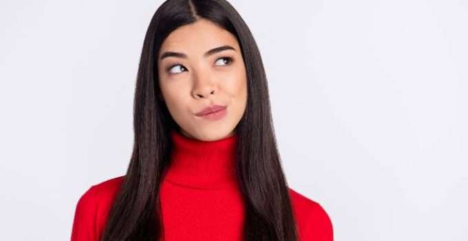 Mujer de cabello liso mira hacia arriba pensativa