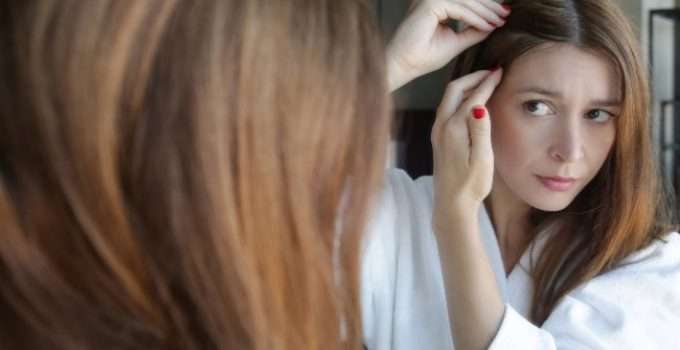 mujer mira que asoman raíces en pelo teñido