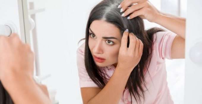 mujer observa sus canas en espejo