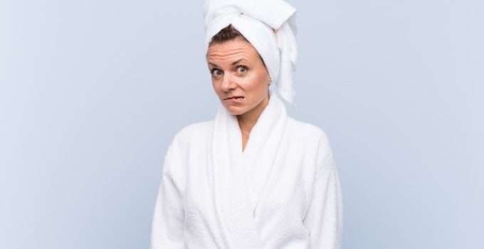 mujer con pelo envuelto en toalla en actitud de duda