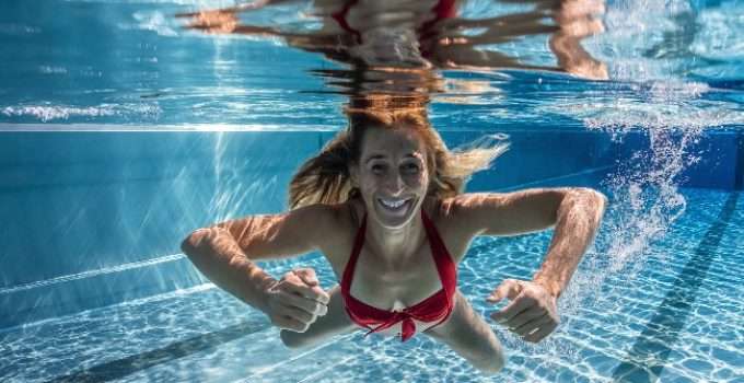 mujer teñida de rubio nadando en piscina