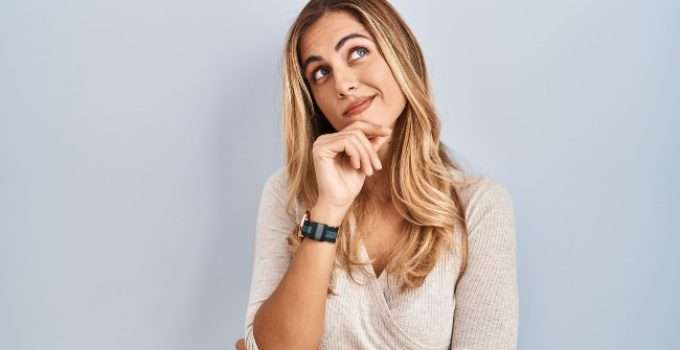 mujer de pelo rubio mira hacia arriba pensando