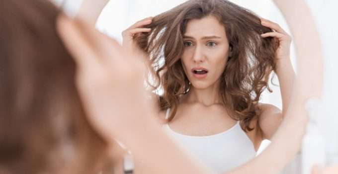 mujer mira en el espejo su color desvanecido