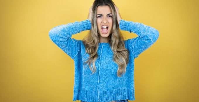 mujer con reflejos grises se agarra a cabeza asustada