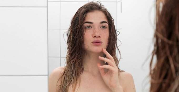 mujer pensativa mirando el color de su pelo al espejo