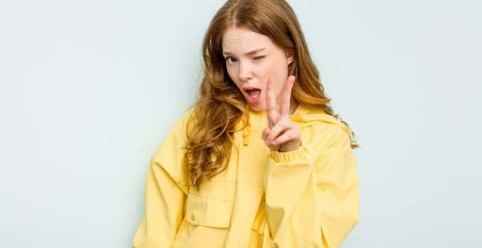 mujer de pelo anaranjado muestra dos dedos