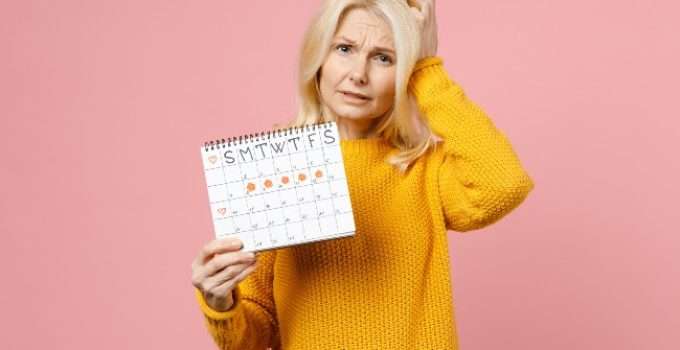 mujer con pelo decolorado sostiene calendario mensual en mano