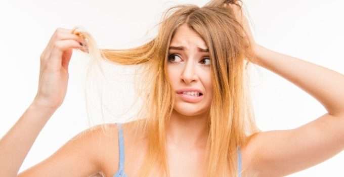 mujer mira con espanto su pelo rubio decolorado