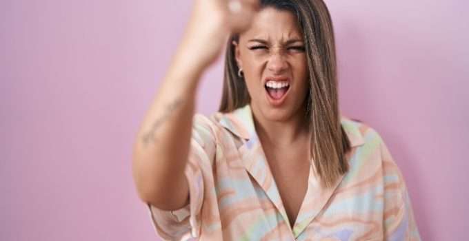 mujer de pelo con reflejos oscuros hace gesto de enojo