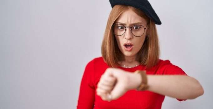 mujer con cabello teñido de rojo mira el reloj pensando en el tiempo