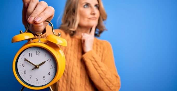 mujer con reloj en la mano piensa en las horas después de hacer el balayage