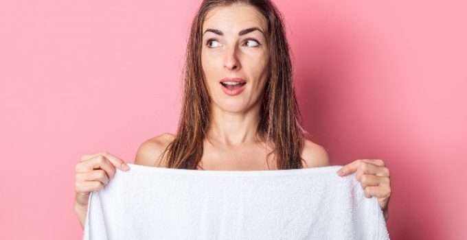 mujer con toalla en mano no sabe si dejar su pelo húmedo o seco