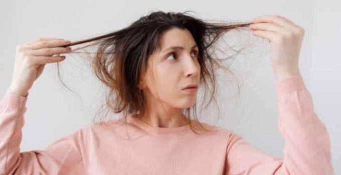 mujer mira su pelo sucio antes de aplicar tinte de caja