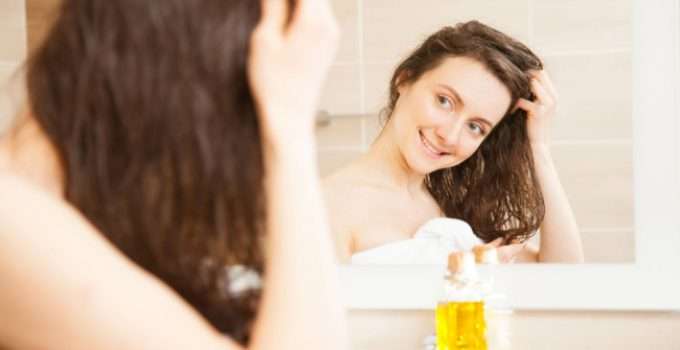 mujer se mira en el espejo mientras aplica aceite de oliva