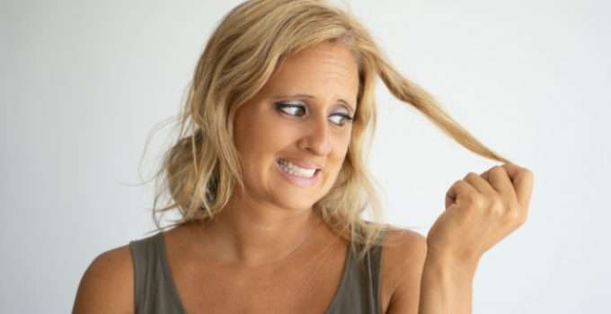 mujer mira su cabello pensando si el tinte sin amoníaco lo daña