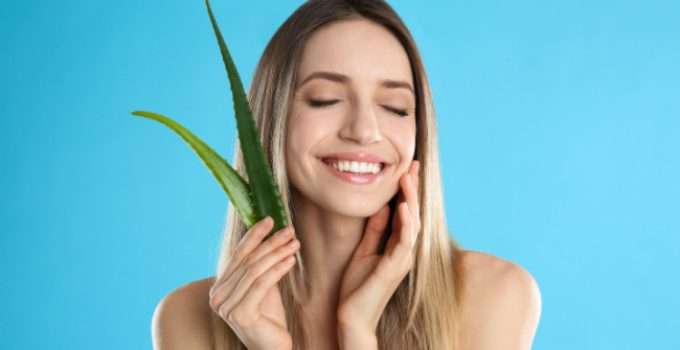 Una muchacha sostiene un trozo de aloe vera para hacerse una mascarilla después de la keratina