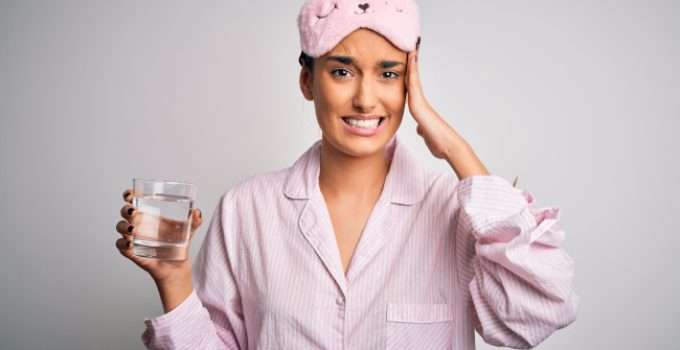 mujer en pijamas con vaso de agua y vinagre diluido
