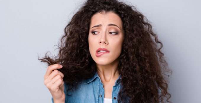 mujer con permanente mira su pelo dañado