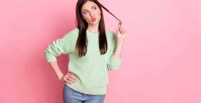 mujer sostiene un mechón de pelo pensativa