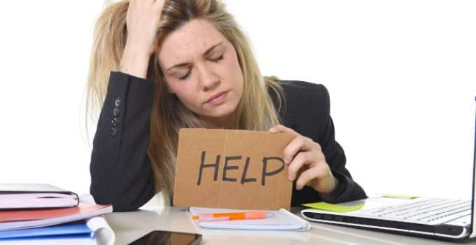 mujer de pelo naranja sostiene cartel pidiendo ayuda