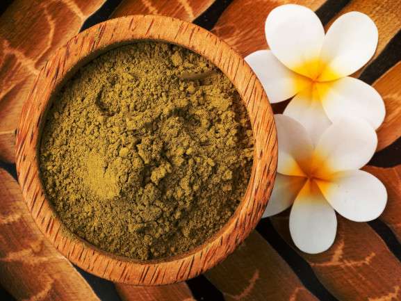 Recipiente con polvo de henna y flores a un costado