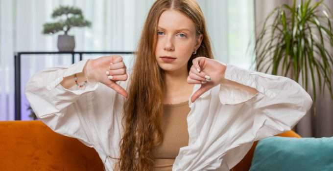 Una chica muestra sus pulgares abajo porque la keratina vence y si se usa corre riesgos la salud capilar