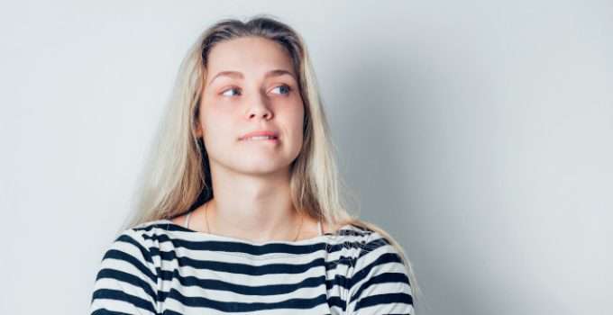 Una mujer con mechas rubias y raíces oscuras se pregunta cómo oscurecer sus mechas a castaño