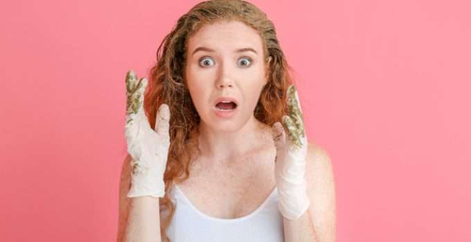 Una joven con gesto de sorpresa ante las contraindicaciones de la henna mientras la usa para teñir su pelo