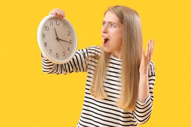 Una jovencita mira el reloj con gesto de desconcierto acerca de cuánto debe dejarse la keratina