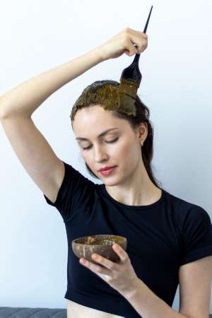 Una chica se aplica henna en el cabello para teñirlo