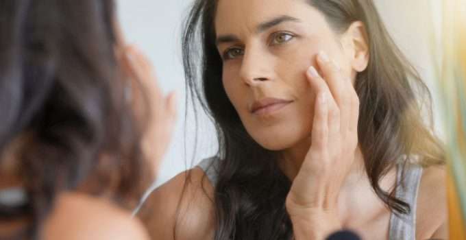 mujer se mira al espejo y toca su piel porque la quiere más blanca