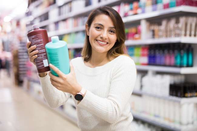 Una señora en la tienda escoge shampoo y acondicionador especial para el cabello tratado
